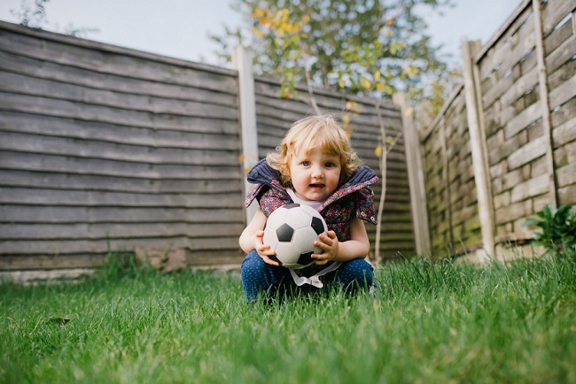 little girl in grass with football