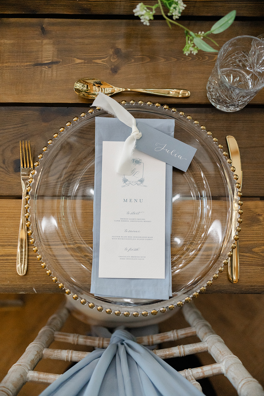 wedding menu on blue linen napkin and glass charger plate