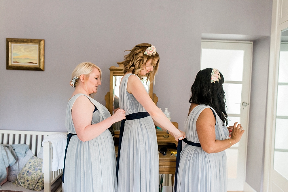 bridesmaids tying dresses
