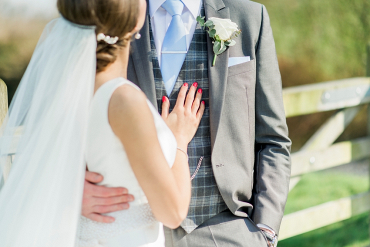 groom in grey suit bride with red nails