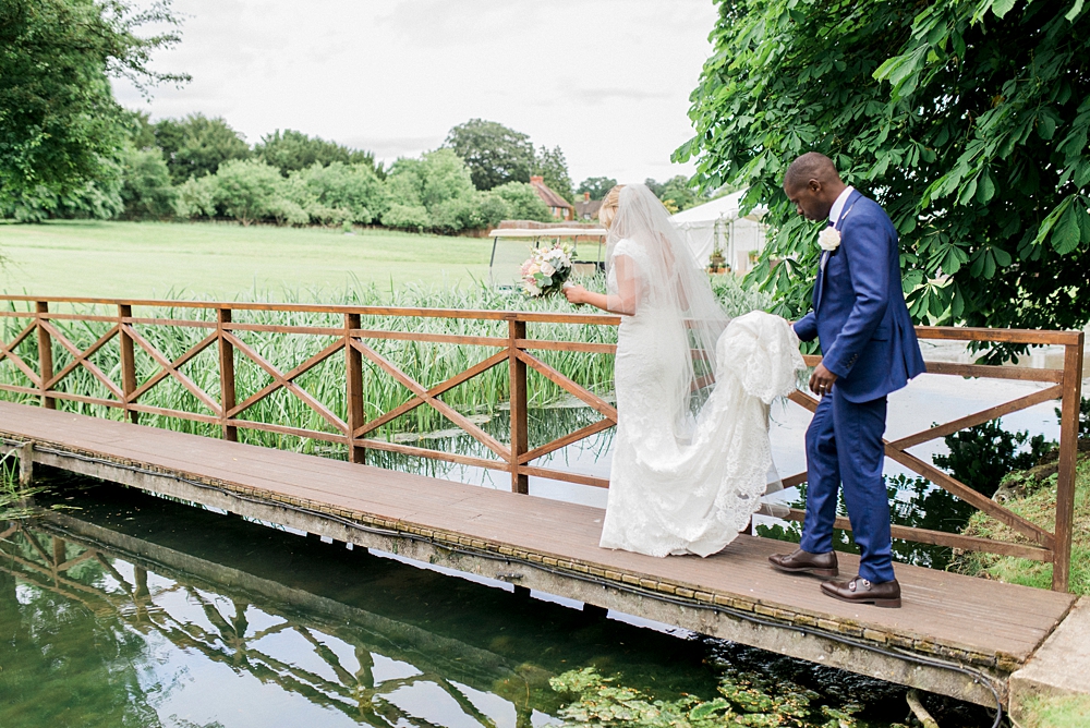 bride and groom walk over bridge at Ardington House