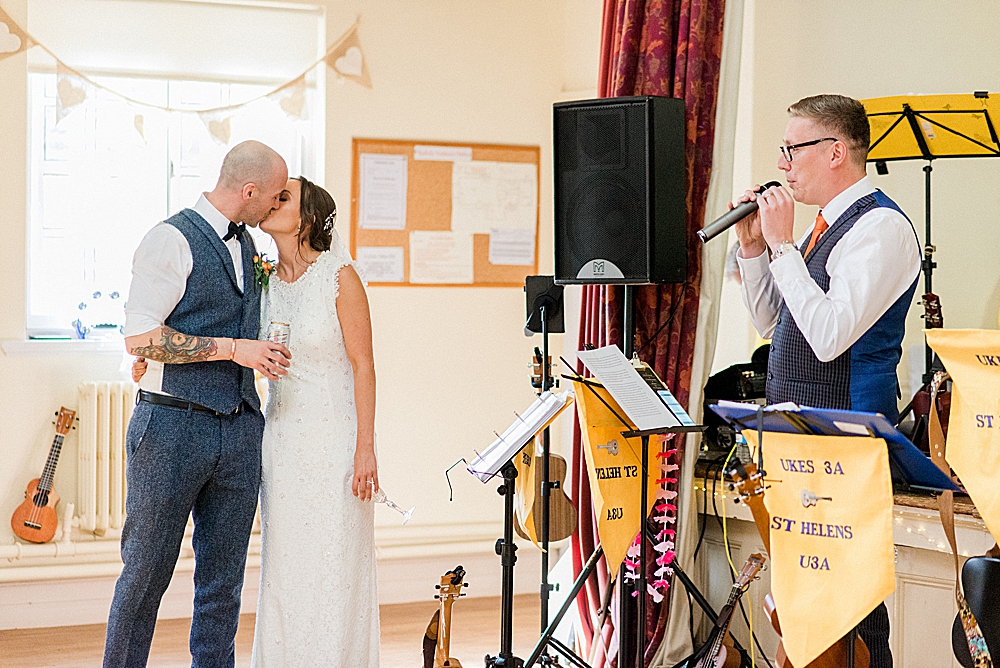 best mans speech at village hall wedding with bride and groom kissing