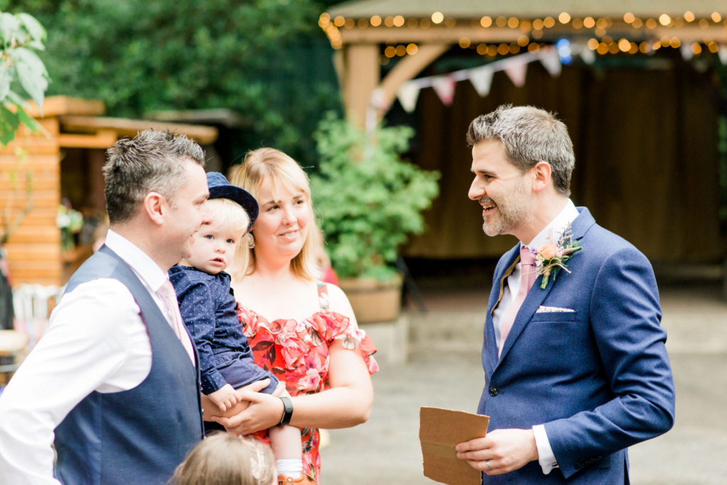 groom chats to guests at outdoor wedding