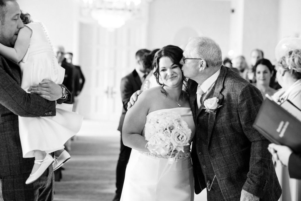 father of the bride kisses daughter at top of the aisle