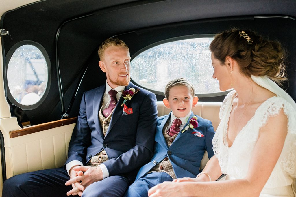 bride and groom with their little boy in wedding car