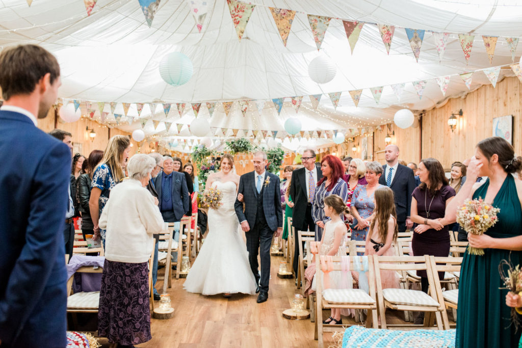 bride and her dad walk down the aisle at wellbeing farm