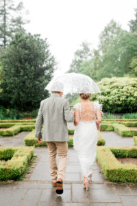 bride and groom under umbrella in the rain