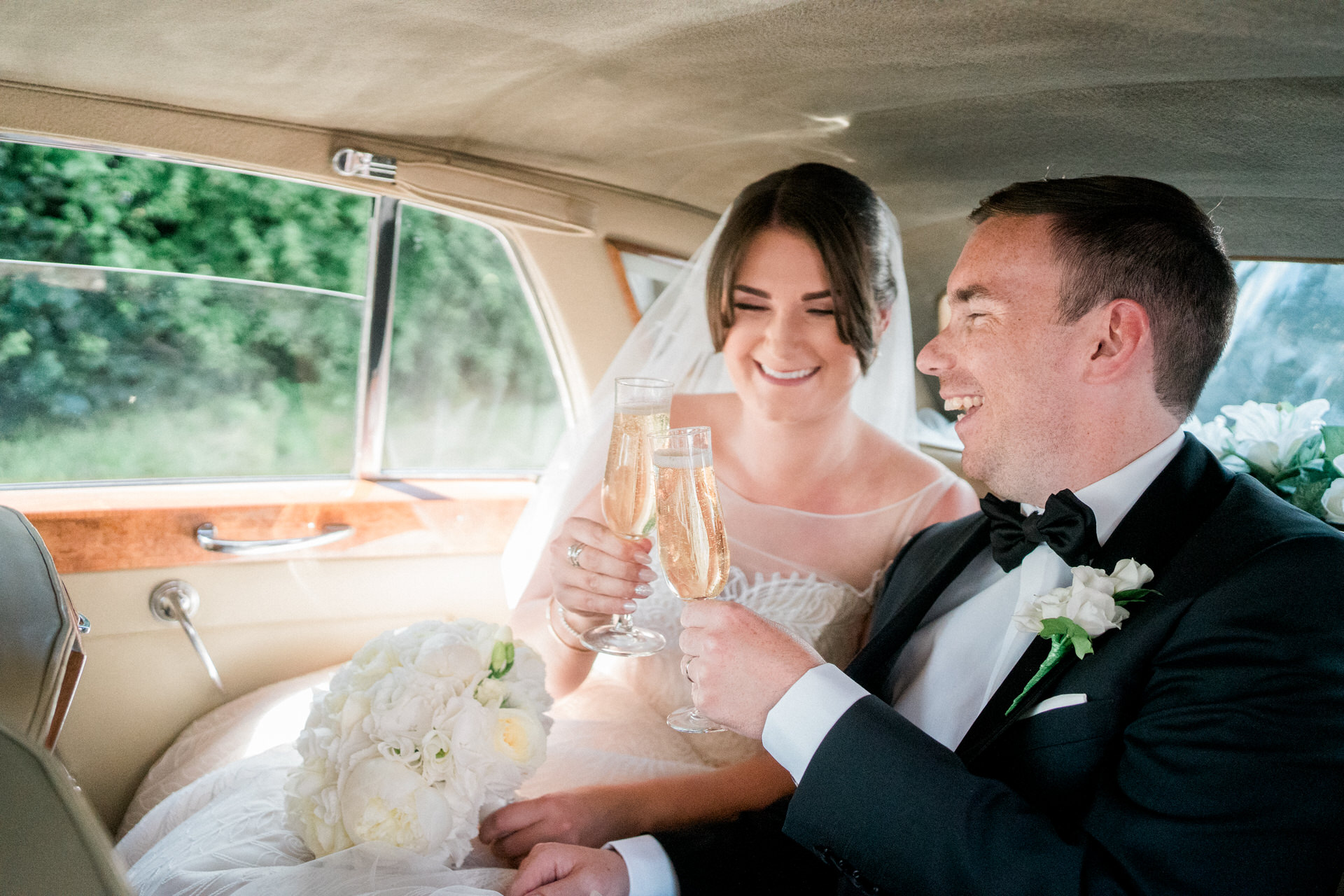 bride and groom in wedding car with champagne toast