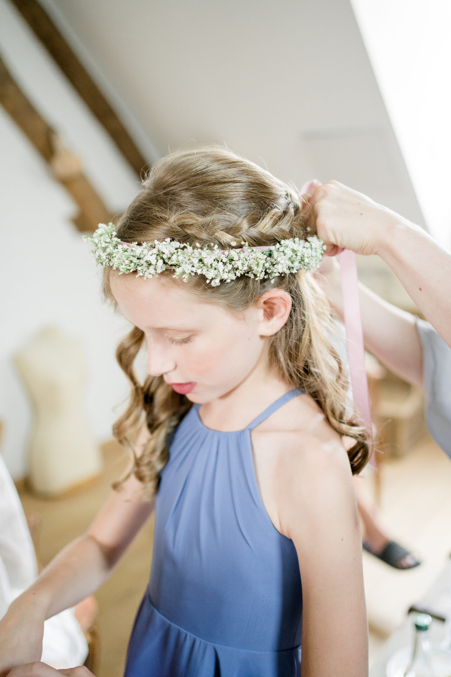 flower girl in blue dress with flower crown being tied