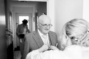 bride putting grandads button hole corsage on