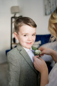 cute page boy smiles at camera wearing tweed suit