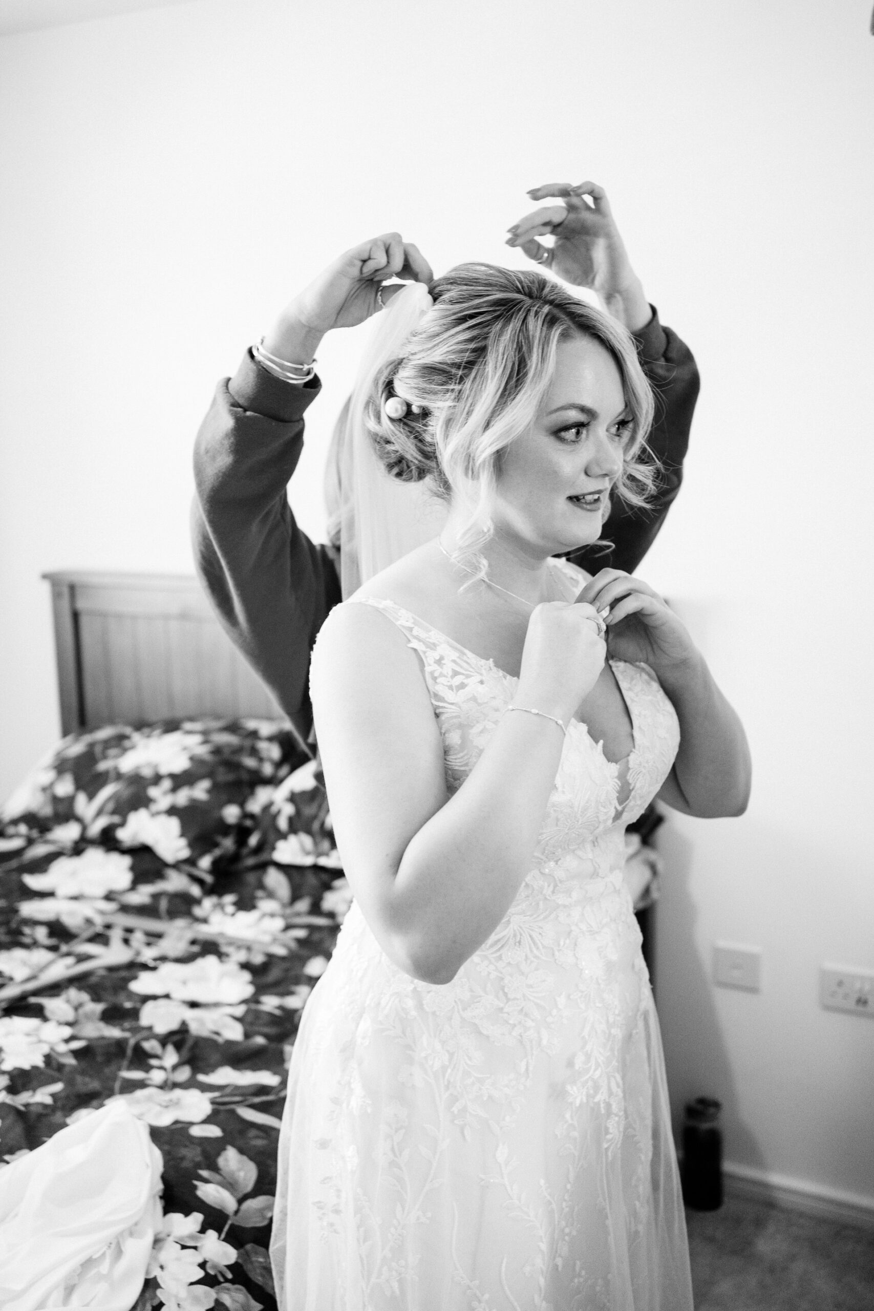 bride having her veil put on by make-up artist, black and white photo