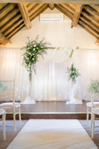 archway with white drapes and green florals at Hyde bank farm wedding venue