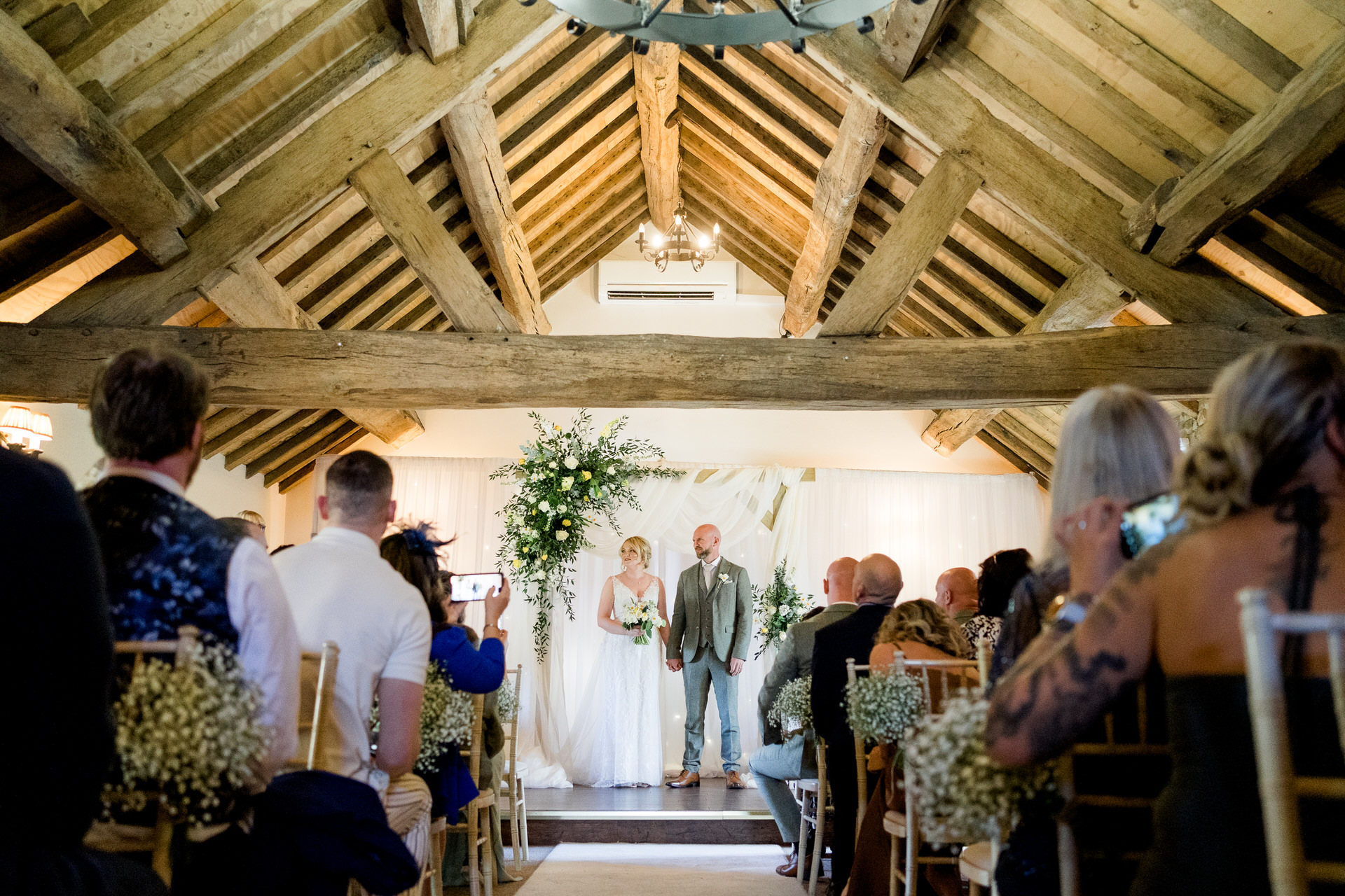 bride and groom standing under arch at hayed bank farm wedding ceremony