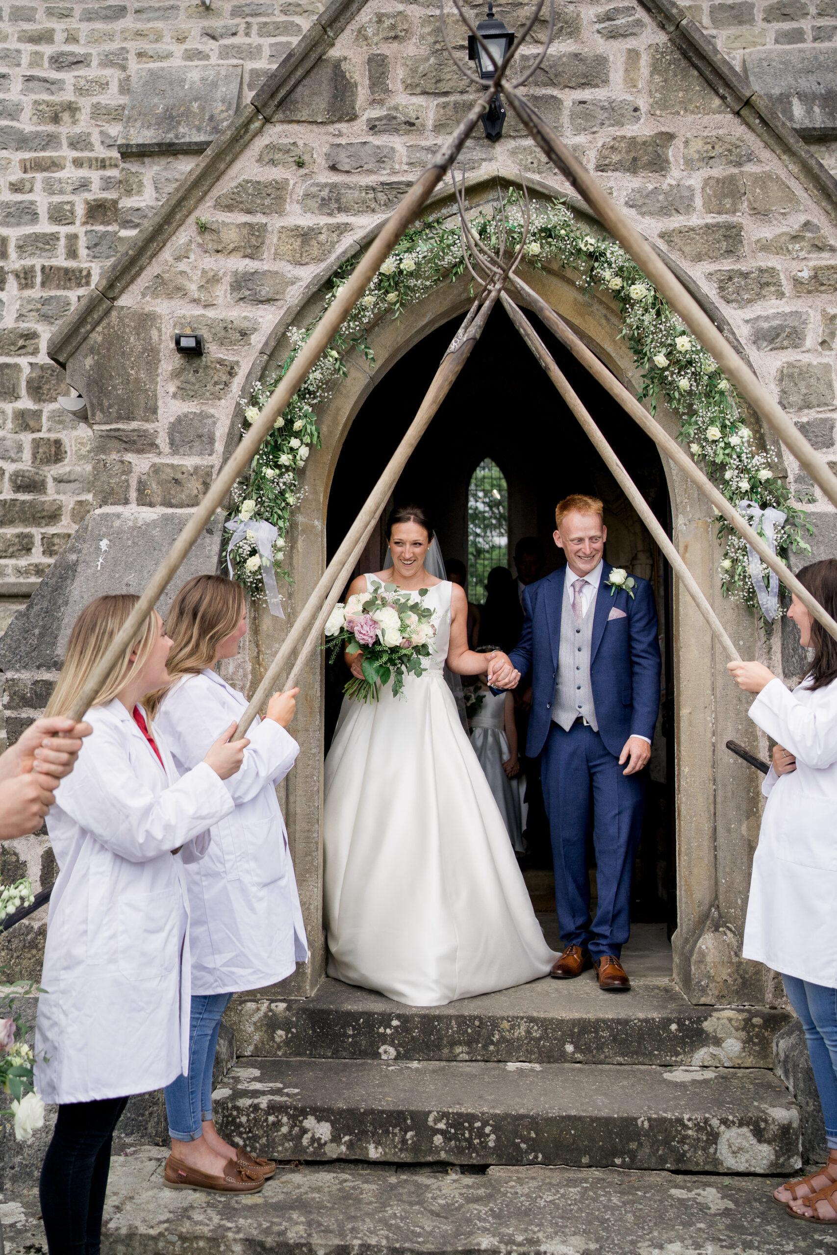 bride and groom leave church to a pitchfork guard of honour, in cumbria