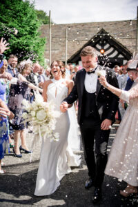 bride and groom walk through confetti tunnel at Rivington hall barn