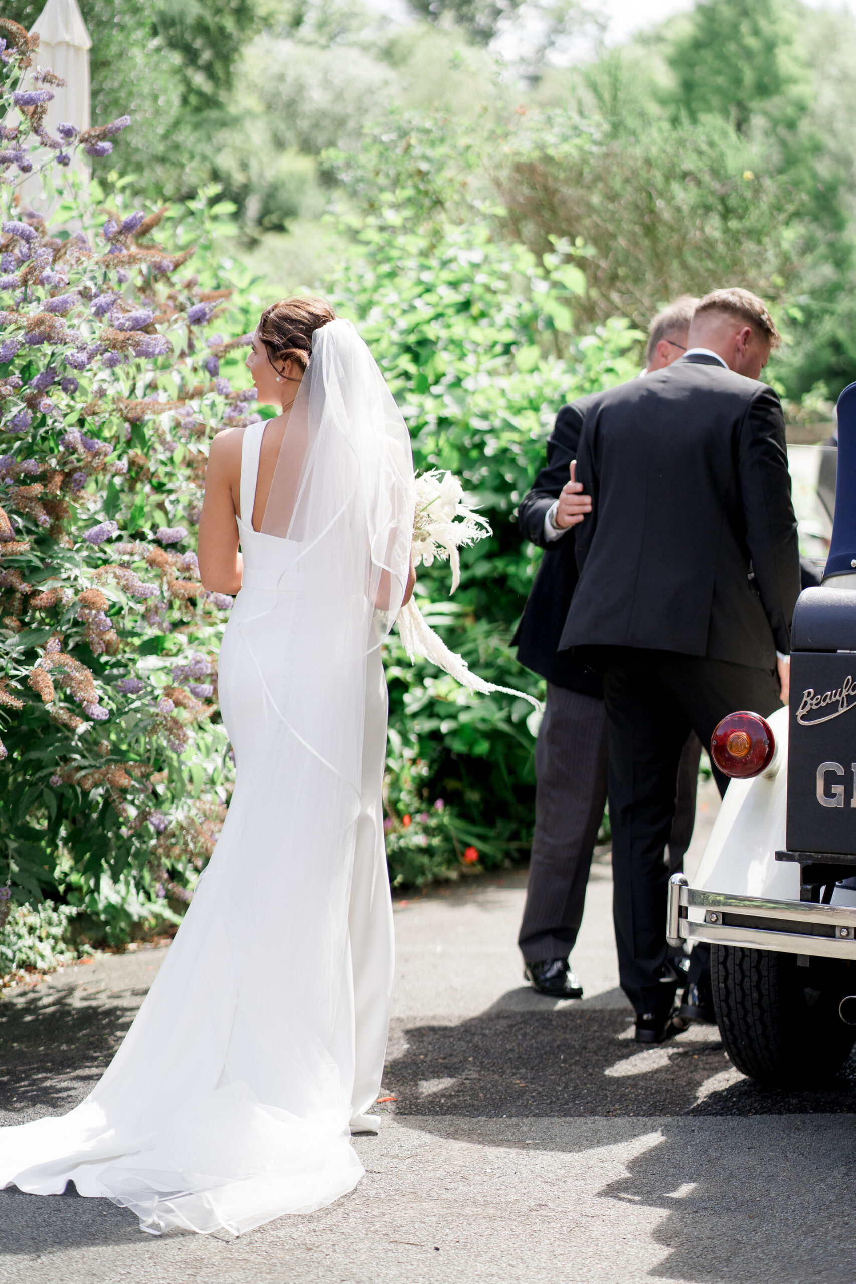 bride and groom about to get into wedding car, photographed from behind