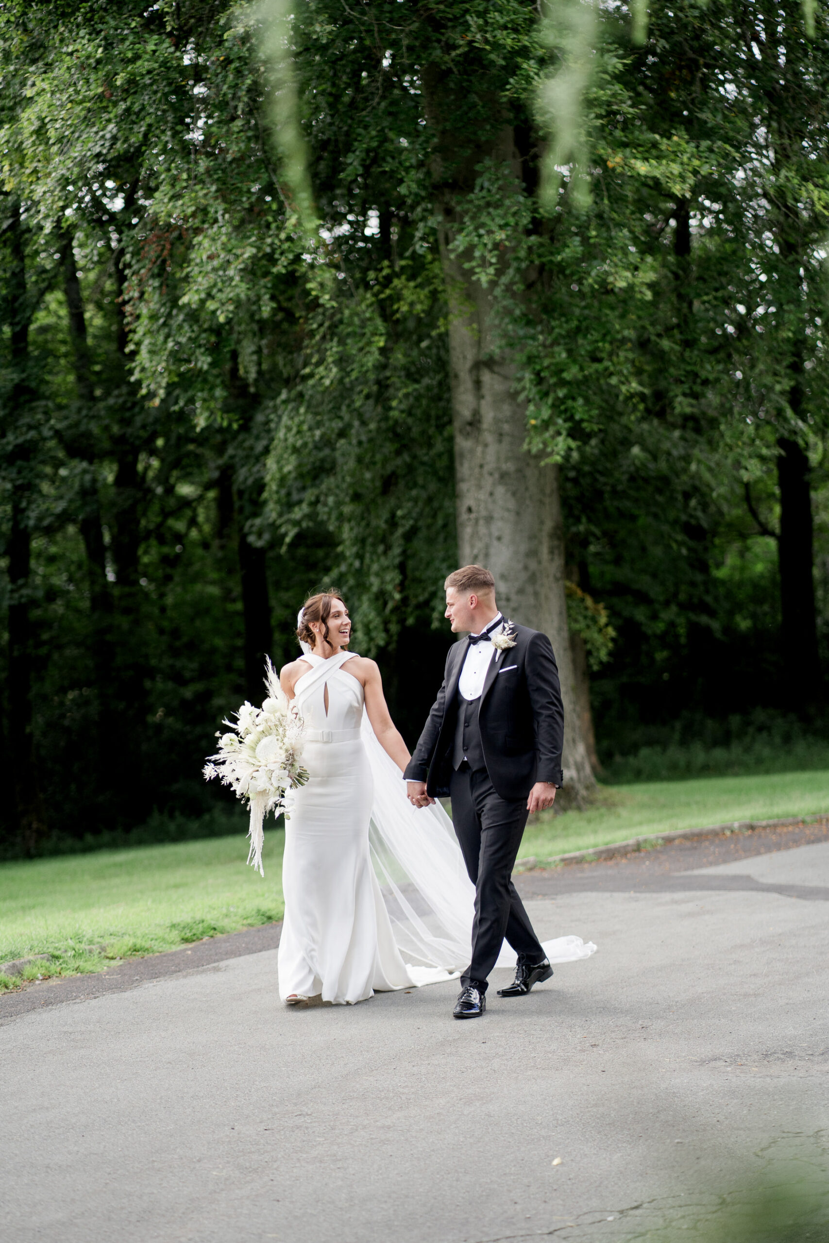 bride and groom walk down driveway at Rivington hall barn for photographs