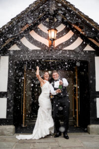 bride and groom pop champagne outside Rivington hall barn