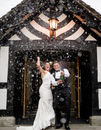 bride and groom pop champagne outside Rivington hall barn