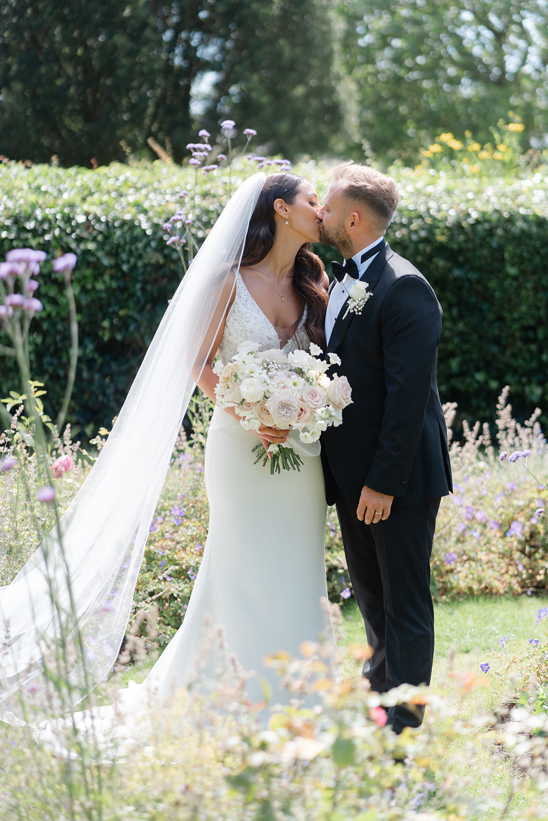 bride and groom kiss amongst the flowers in lowther gardens