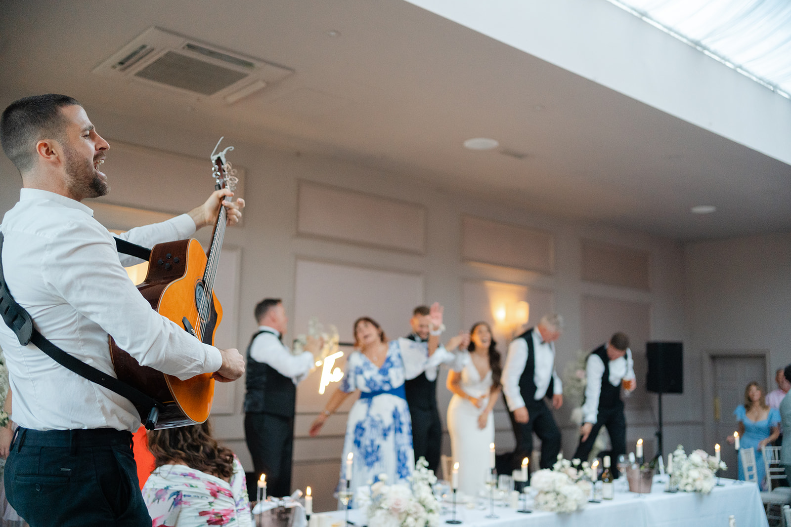 epic wedding party at the Clifton arms in lytham, with guitarist singing and guests dancing on chairs