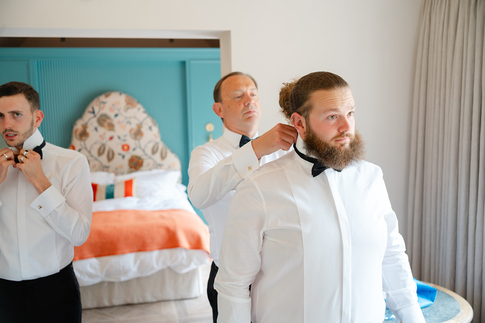 father of the groom adjusting groomsman's bow tie