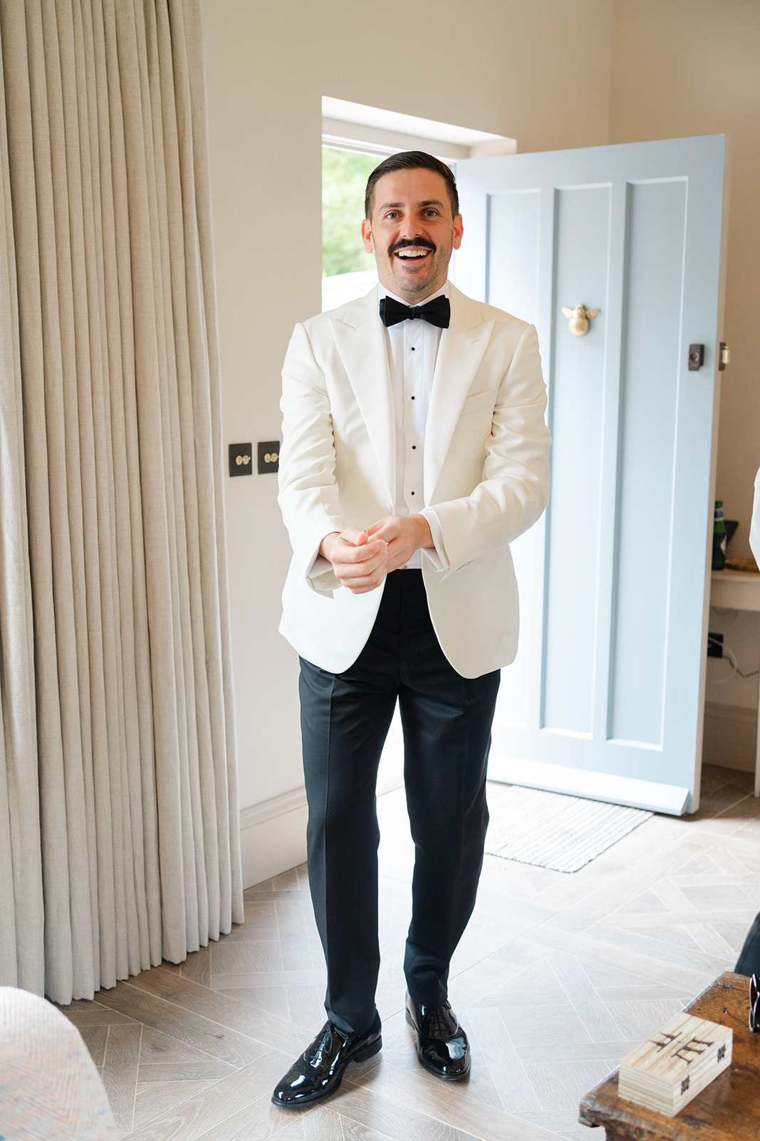 groom in white tux adjusting his sleeves