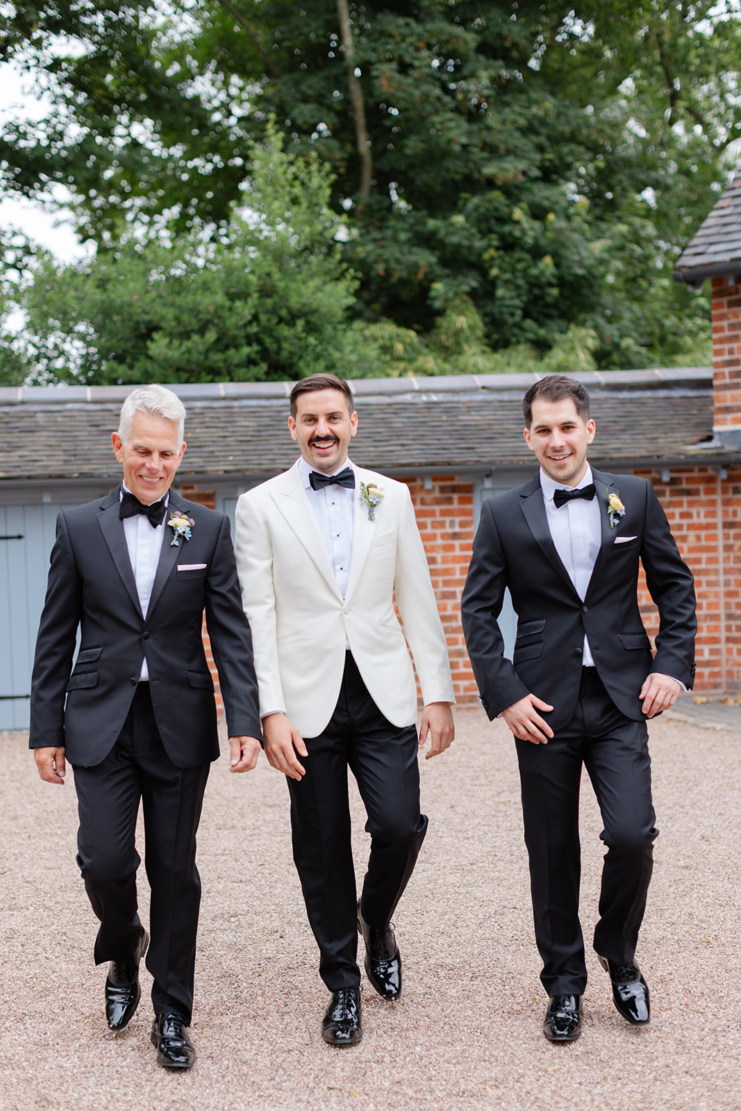 Groom in white tux with father of the bride and brother of the bride wearing black suits