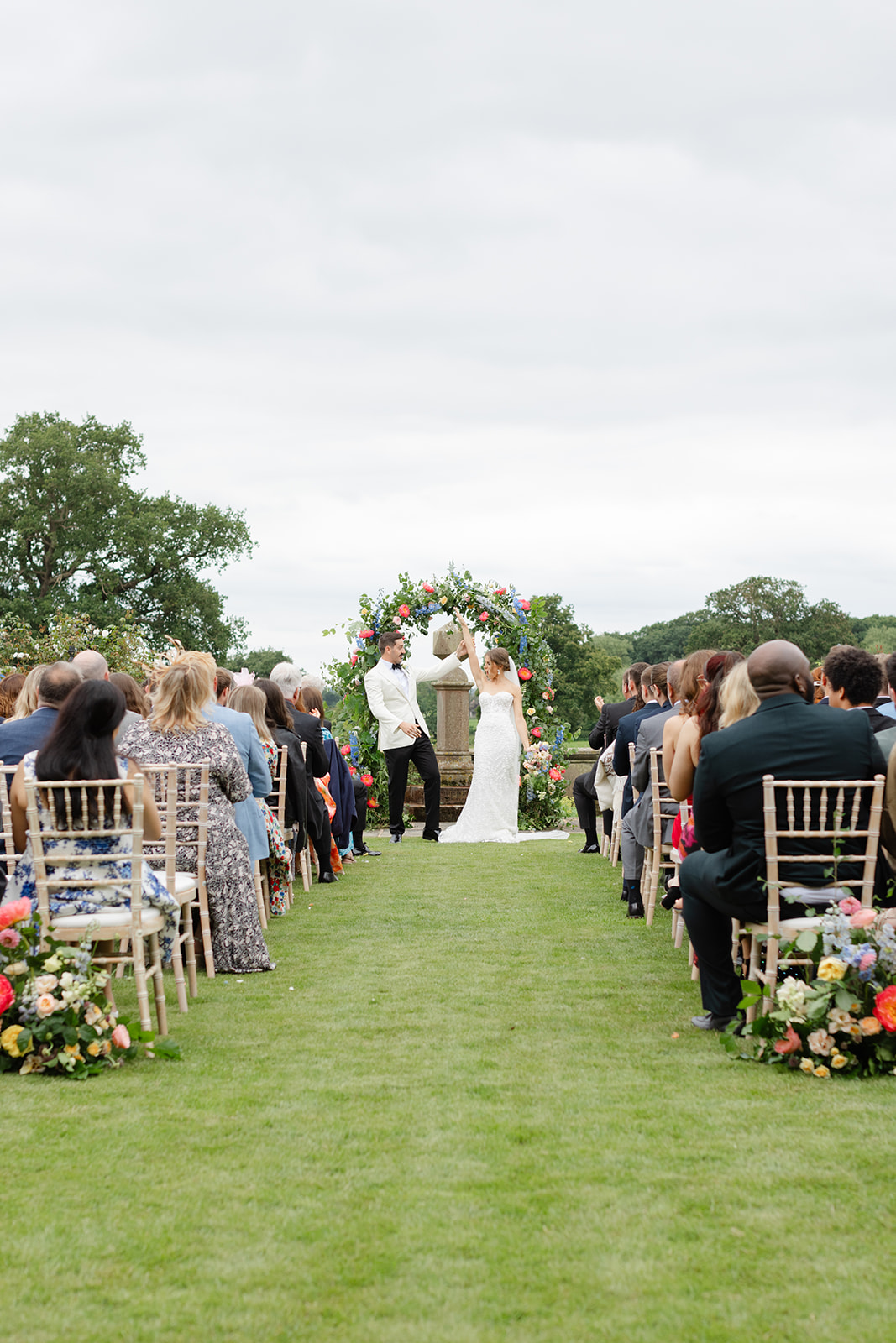 The bride and groom celebrate by raising their joined hands as they are announced as husband and wife