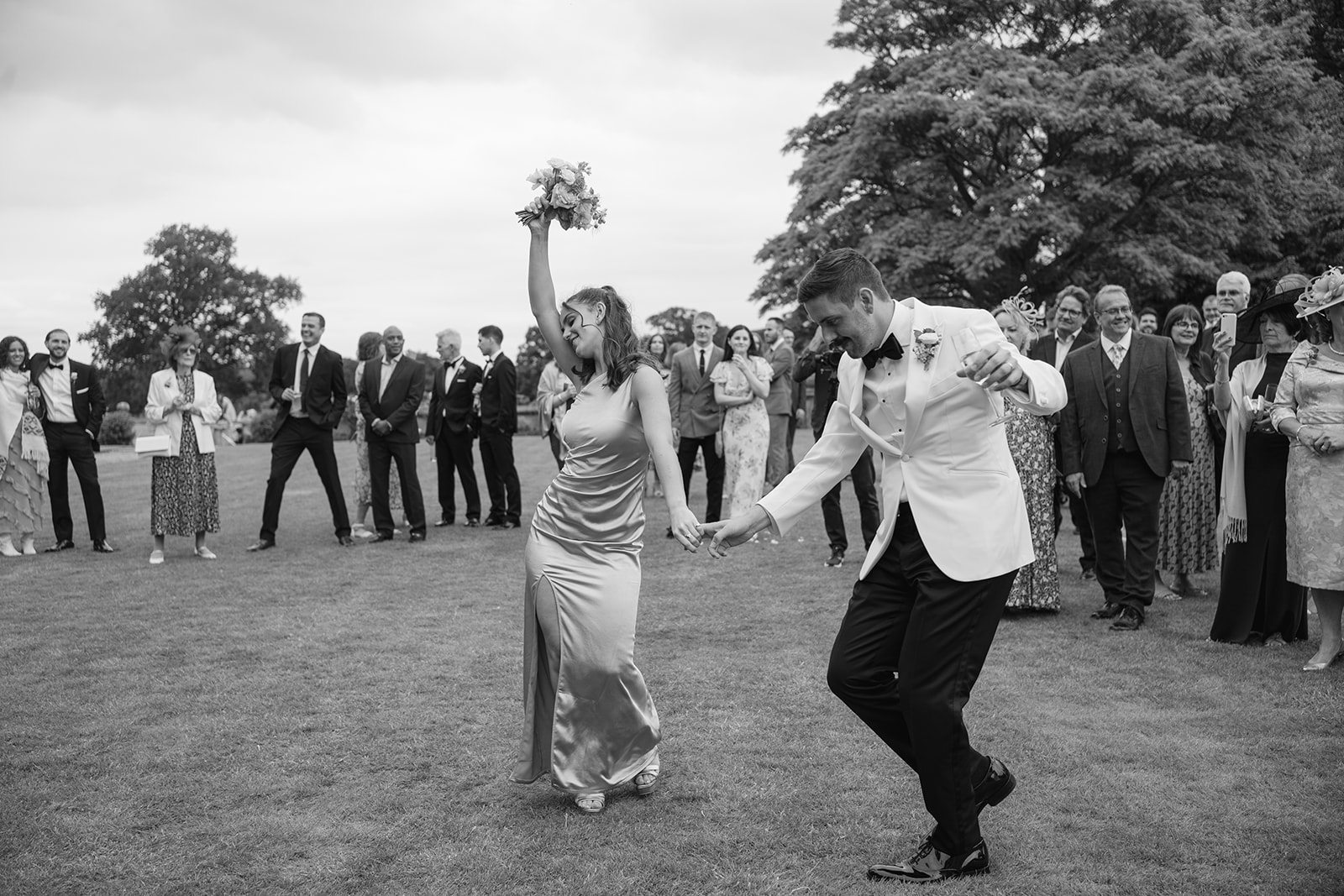 groom and his sister dancing on the lawn at fourfold hall, she holds her bouquet in the air
