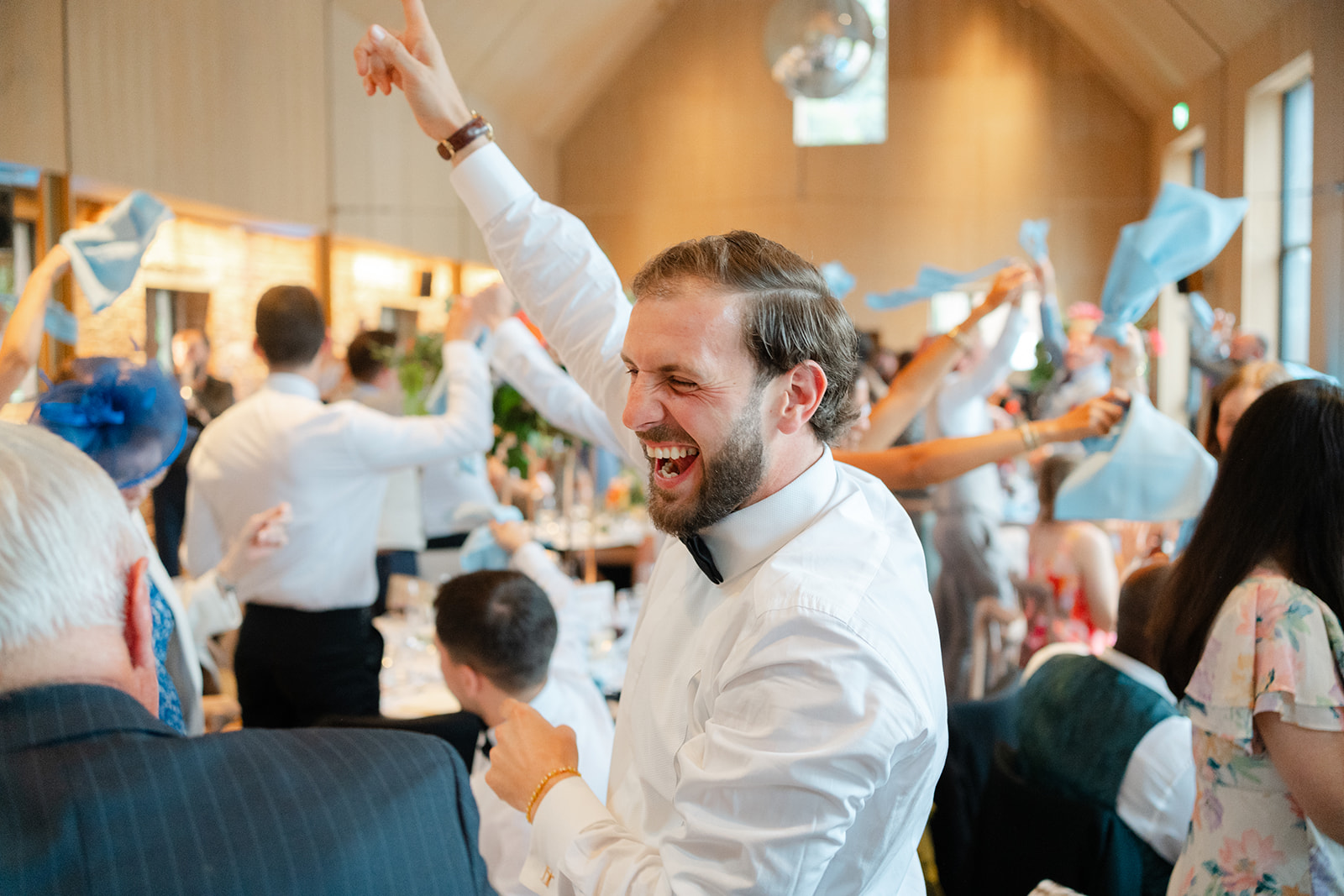 elated groomsman cheers and points finger to the sky whilst dancing