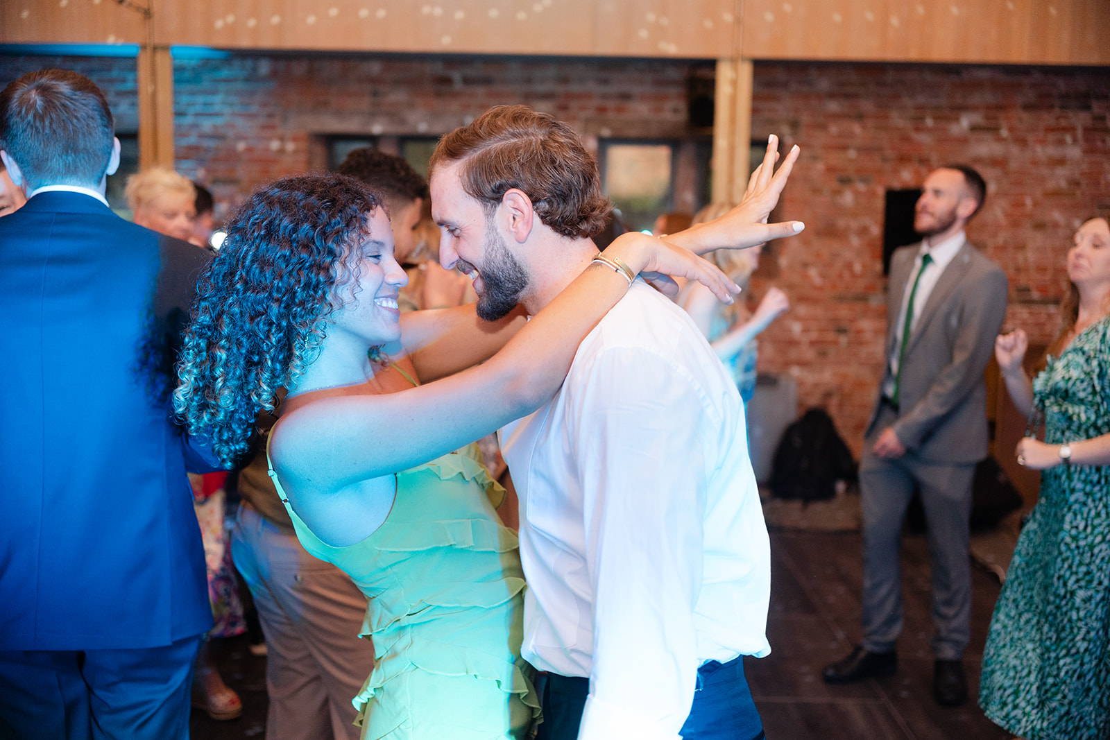 wedding guests with arms around each other and smiling on the dance floor