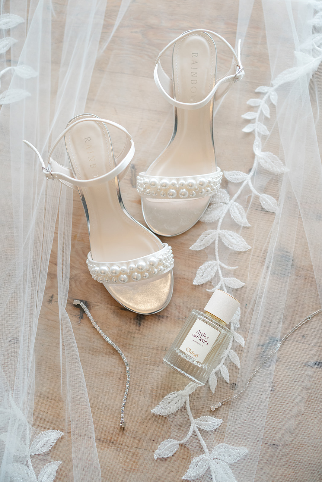 wedding shoes, perfume and jewellery sitting on veil