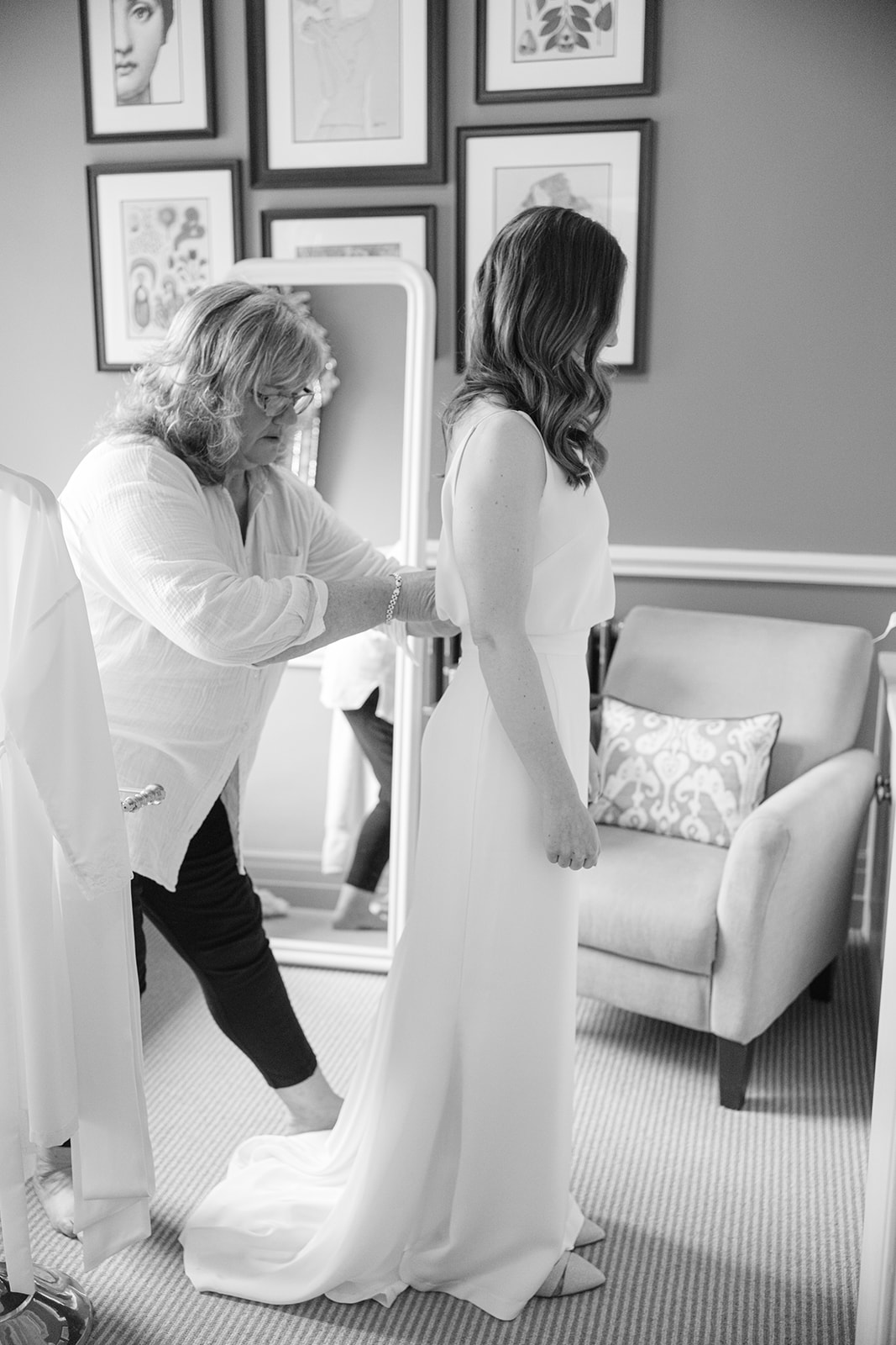 bride has her dress fastened by mum