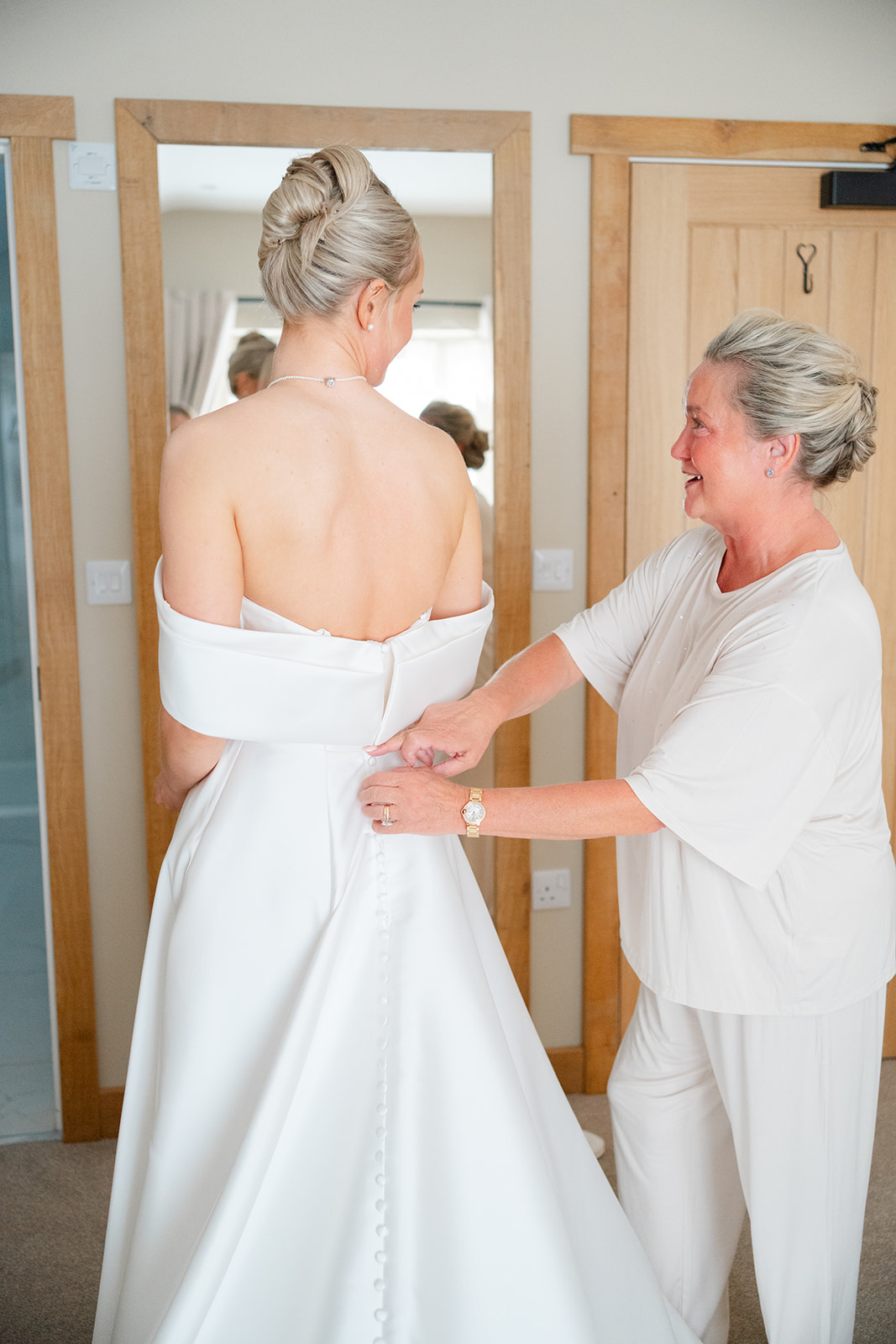 bride's mum helping her daughter into her wedding dress at hobbit hill wedding venue