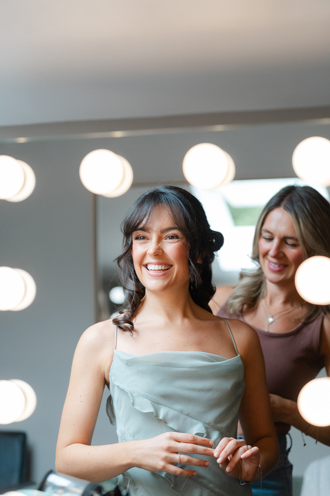 bridesmaid in sage green smiles at her reflection