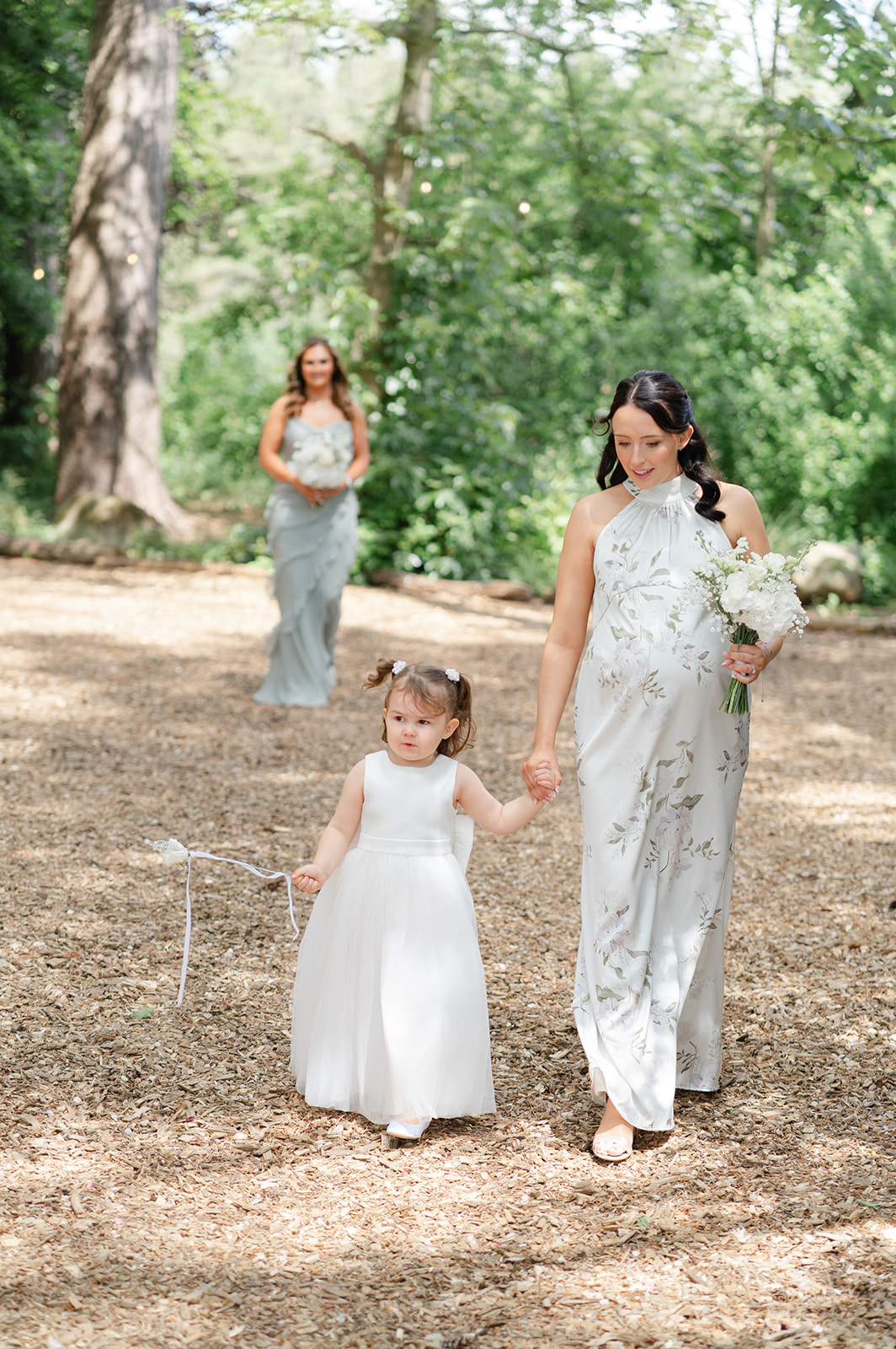 pregnant maid of honour and tiny flower girl walk down the aisle together