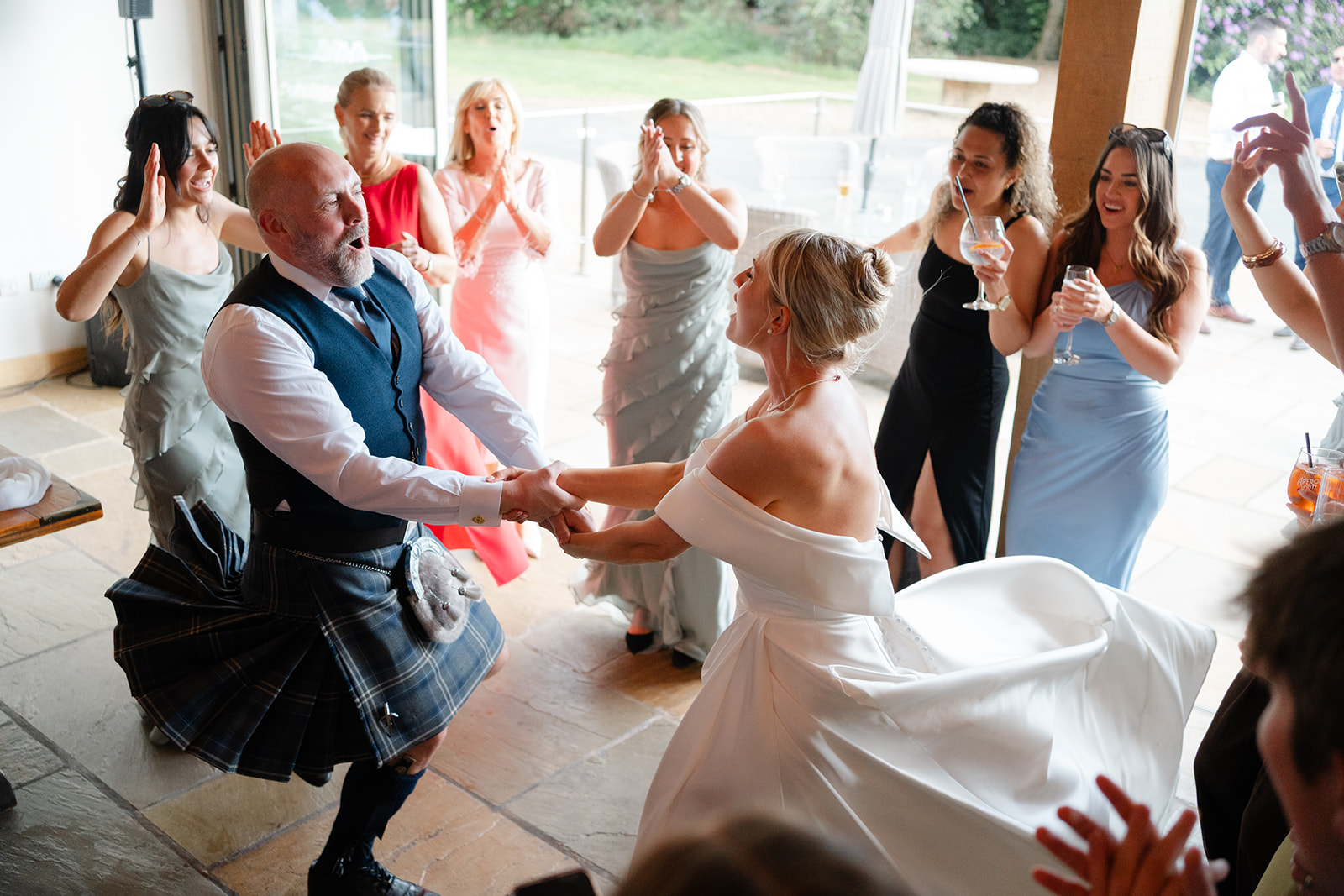 bride dances with guest who is wearing a kilt