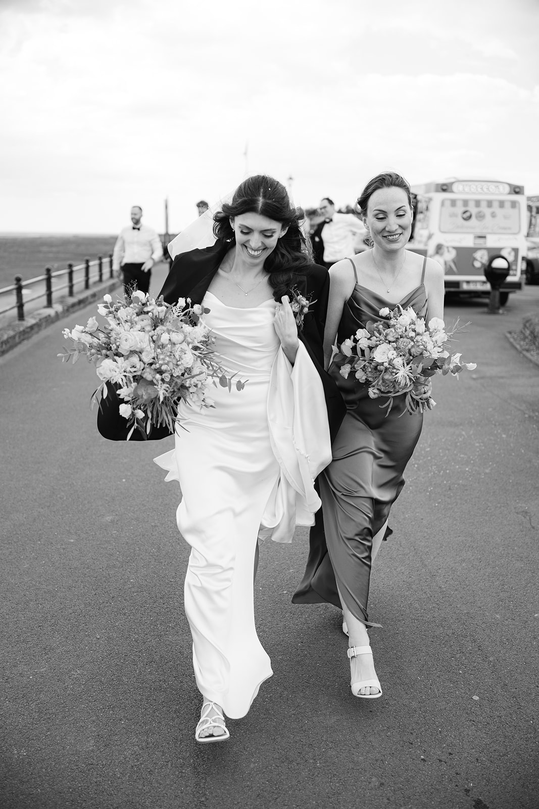 bride and her maid of honour brace the wind on the seafront at Lythm